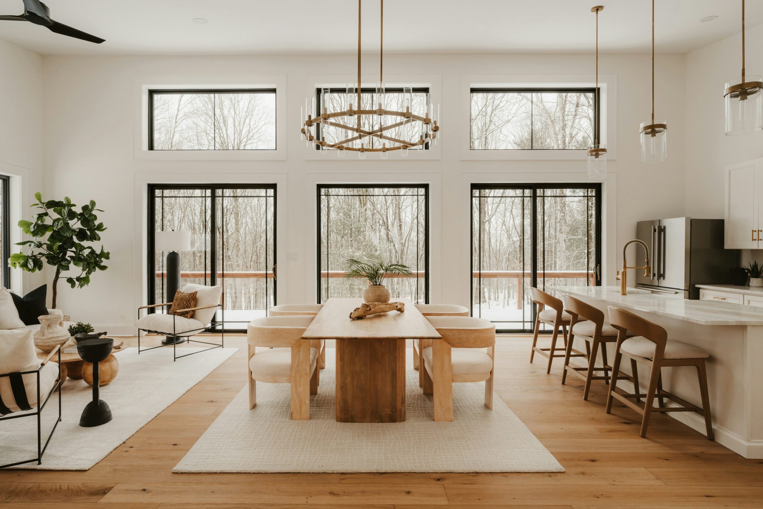 Bright open-concept dining room with a wood table, cream chairs, and kitchen island seating staged for local sale in San Antonio.