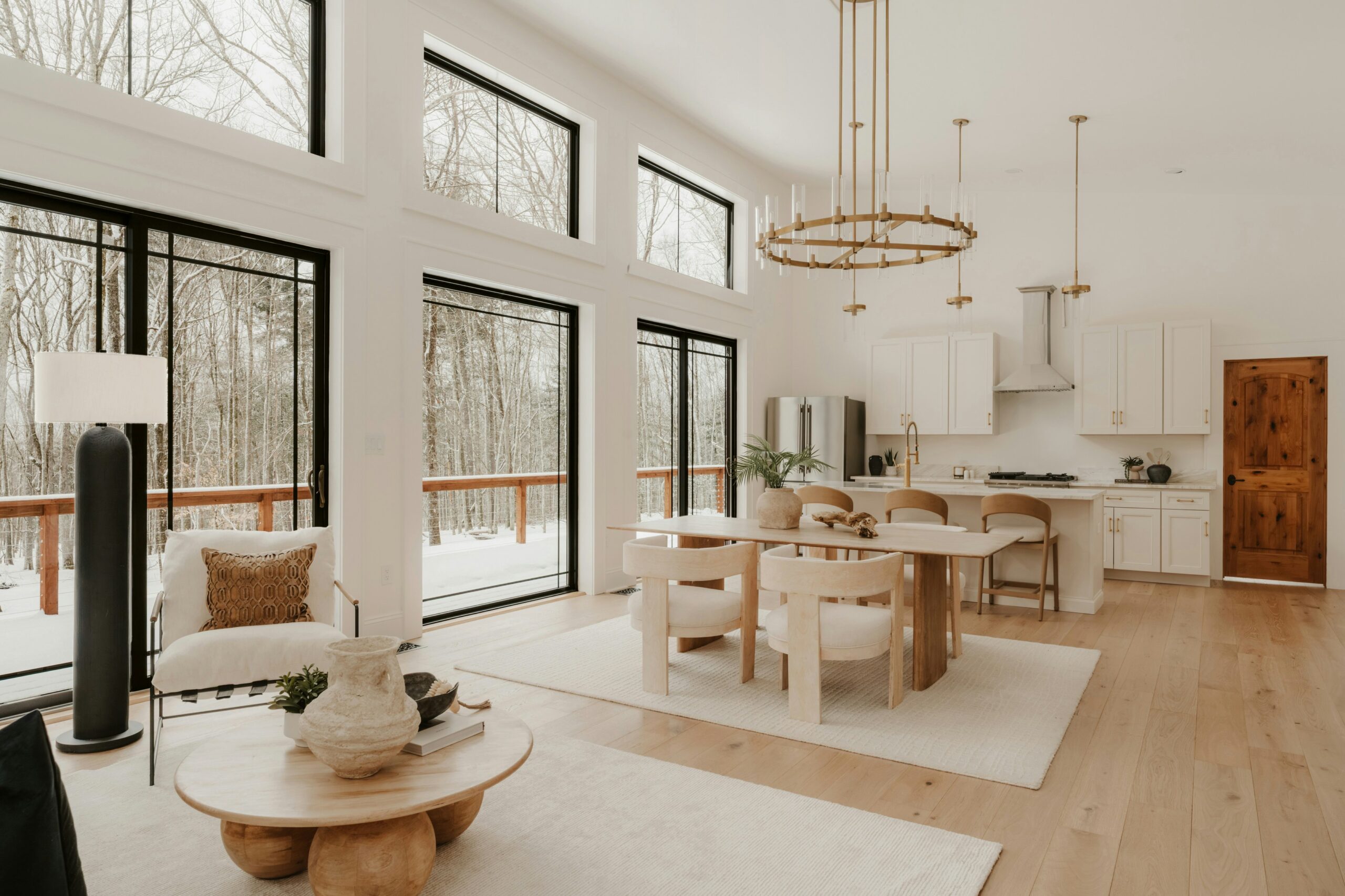 Modern open-concept living and dining space with large windows, a wood dining table, lounge chair, and round coffee table prepared for local pickup in San Antonio.