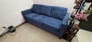 Blue upholstered sofa with dark wood base frame